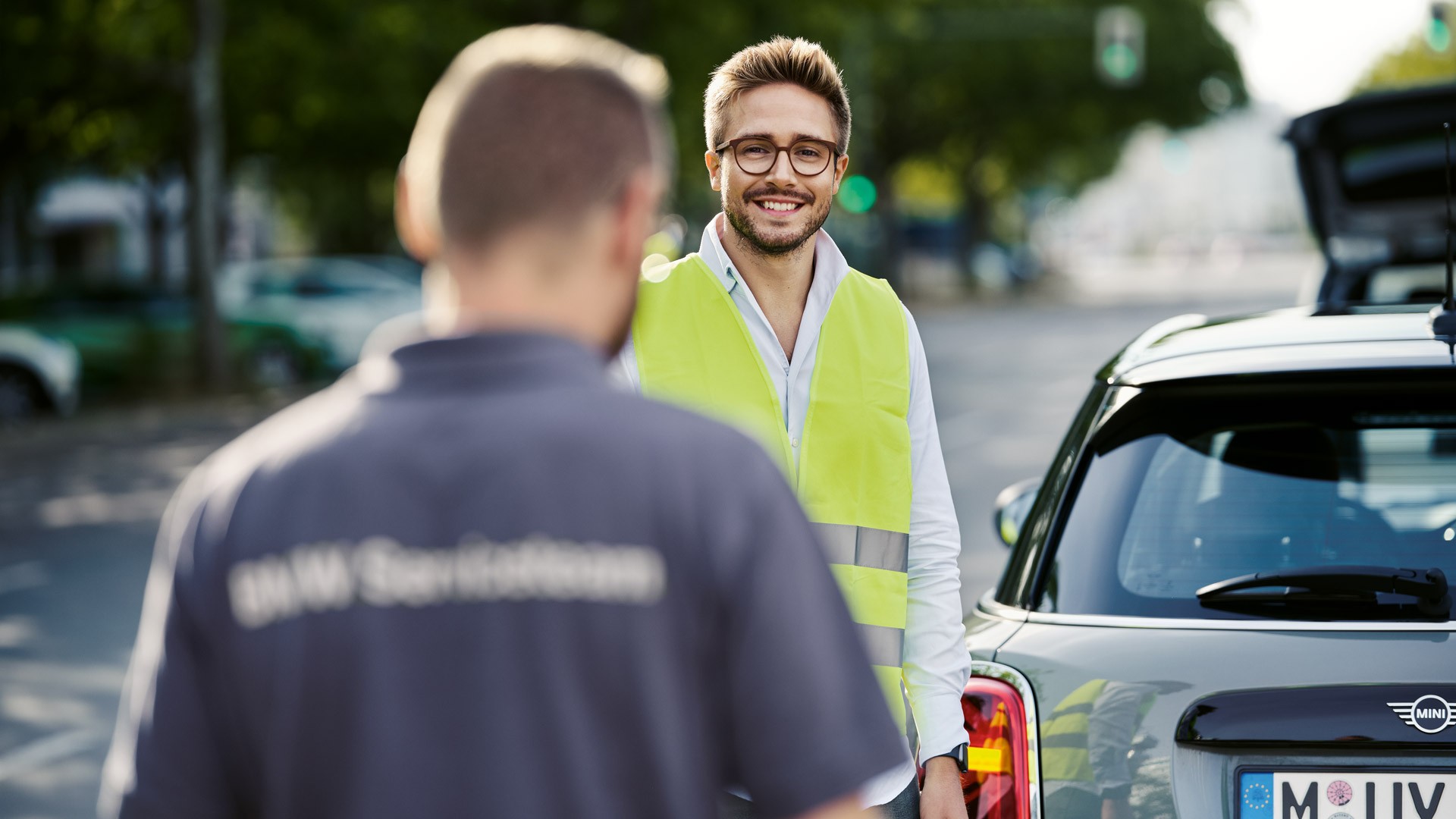 Roadside assistance technician speaking with a MINI driver next to a MINI in White Silver Metallic.